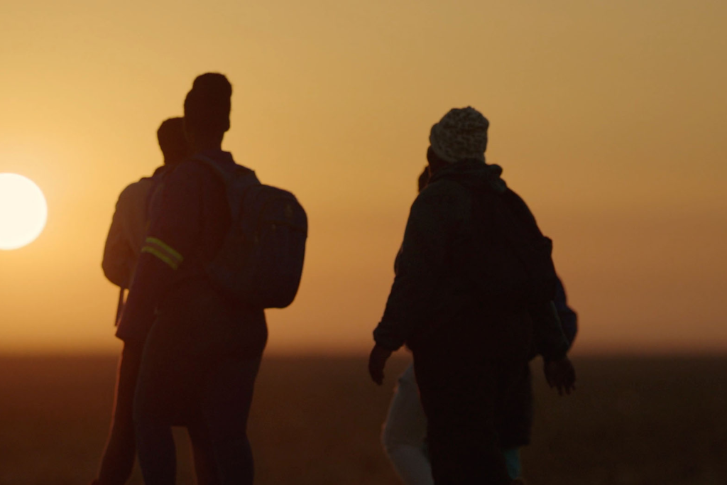 Two people walk toward a setting sun in Africa